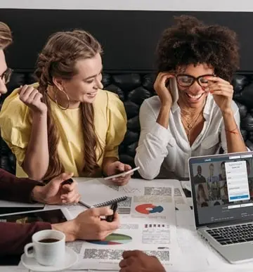 Profissionais analisando gráficos de marketing com notebook em videoconferência durante reunião de equipe.